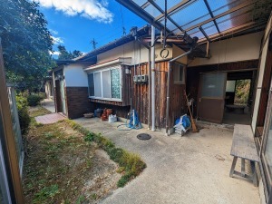 木造平屋建てでL字に建物が造られ、玄関と土間の入口がある物件の外観写真