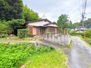 後方が林になっており、細い道路沿いに建つ住宅で、ブロック塀に囲まれた平屋建ての物件の写真