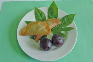 納豆ギョウザ2個とブドウ2粒が白いお皿の緑の葉っぱの上に並べられた写真
