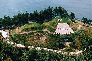 神花山の山頂部に丸い形で最上部がフェンスで囲われ段になっている神花山古墳全体を上空から写した写真