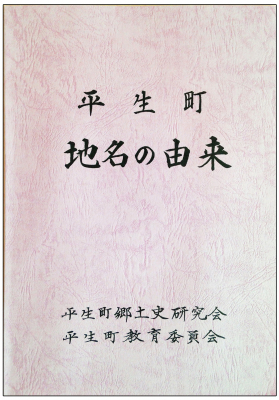 縦長の長方形で、白地に赤い線が波打ったような色合いの、平生町地名の由来と題された本の表紙