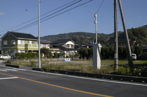 道路横に「売地」と書かれた看板が立つ土地を写した写真