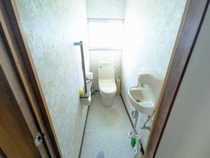奥に洋式トイレがあり手前右側に手洗い場があるトイレ内を写した写真