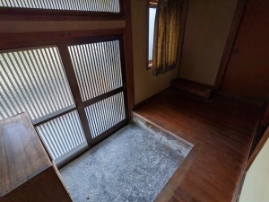 引き戸の玄関と小上がりになっている玄関前の室内を写した写真