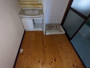 洗面台の横に洗濯機置き場が設けられている板の間の脱衣所の写真