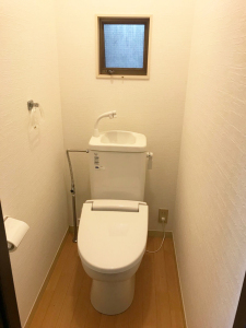 壁が白で奥に小さな小窓がある洋式トイレの室内を写した写真