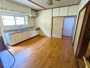左手にキッチン、奥と右手から出入りできる扉があるフローリングの台所を写した写真