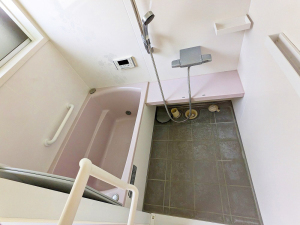 左手に薄いピンク色の浴槽、正面にはシャワーがある浴室内の写真