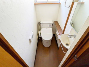 扉を開けて右手に手洗い場、奥に洋式トイレがあるトイレ内を写した写真